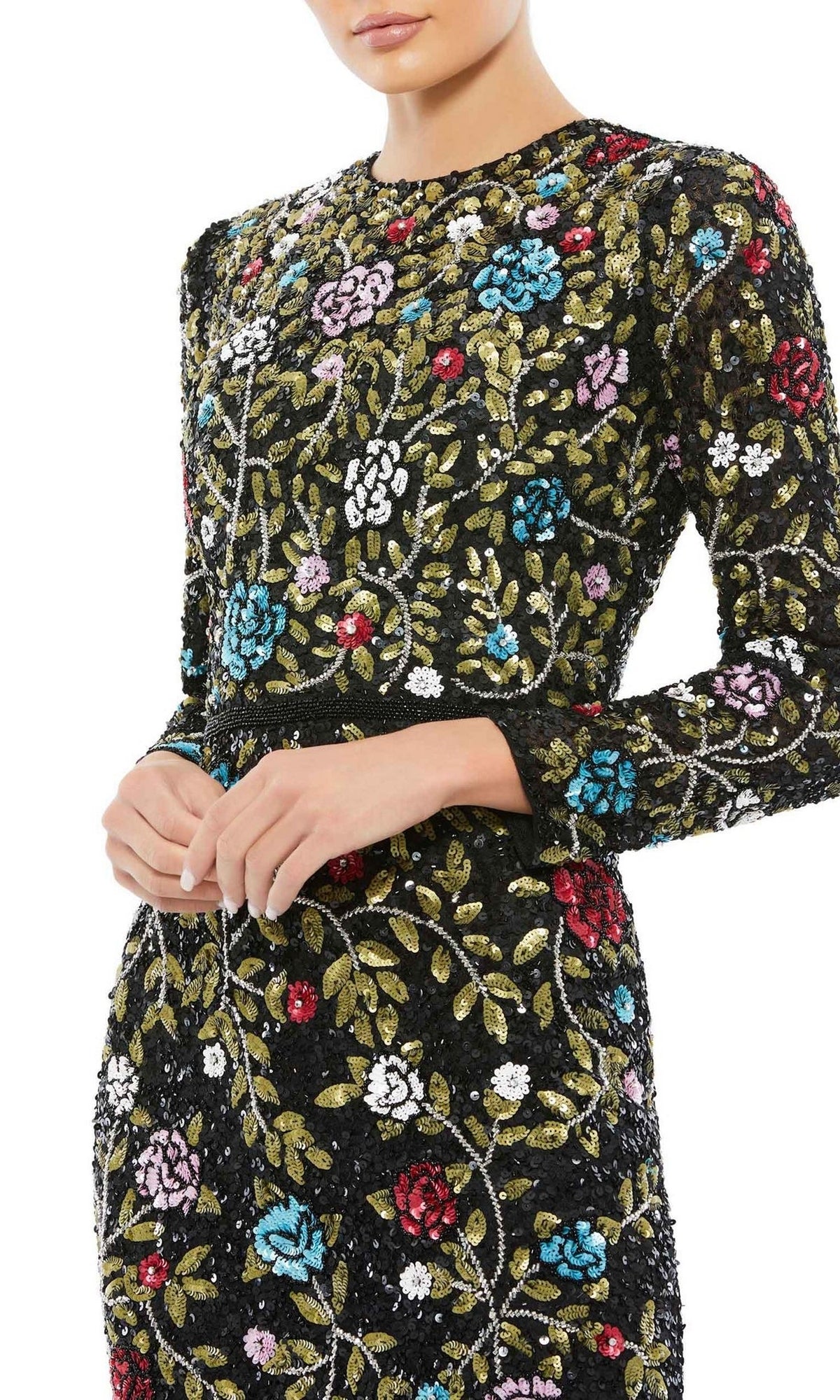A woman stands with hands clasped in the Mac Duggal 5556—an elegant long black print formal dress adorned with colorful embroidery and sequins, perfect for any special occasion.